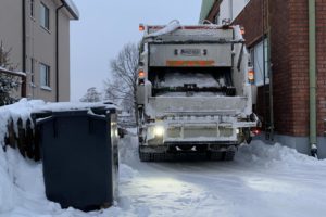 Jäteauto peruttaa taloyhtiön ahtaaseen ja lumiseen pihaan.
