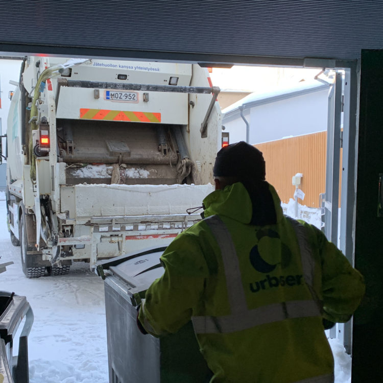 Jäteautonkuljettaja vie jäteastiaa autolle