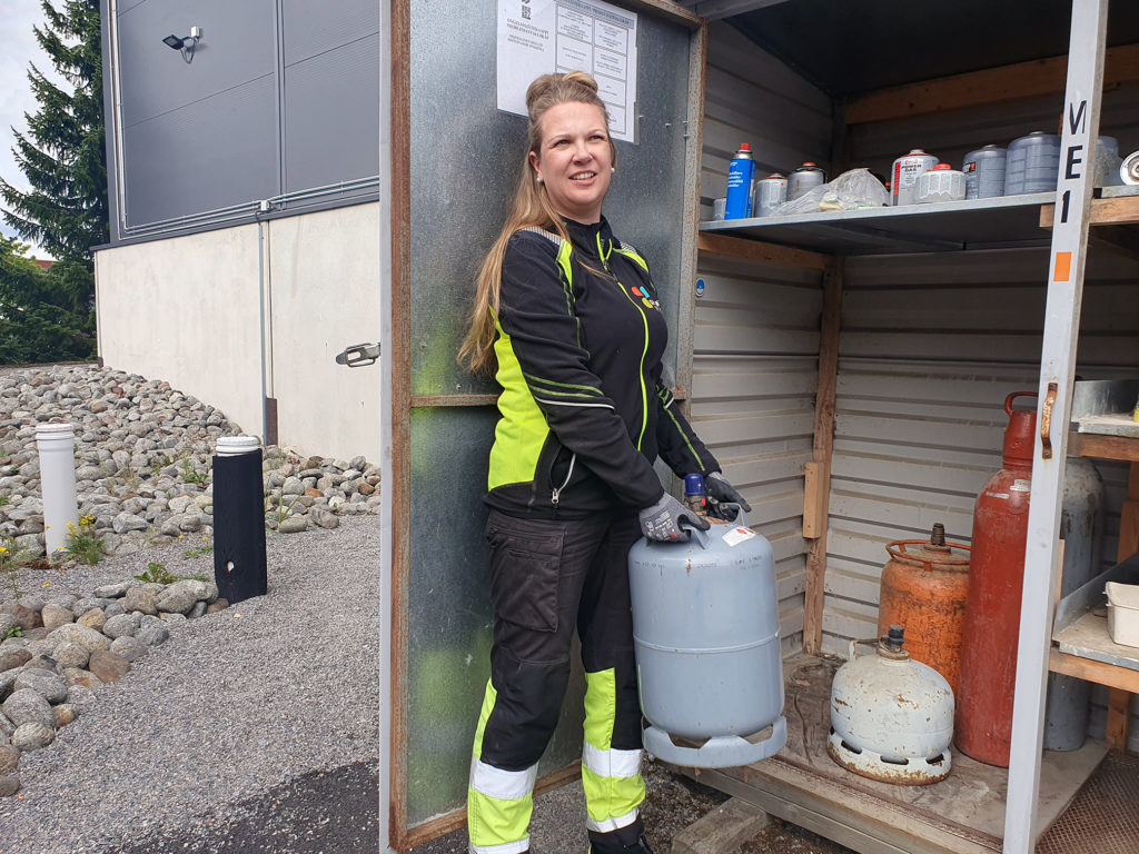 Palveluneuvoja jäteasemalla kaasupullojen kanssa