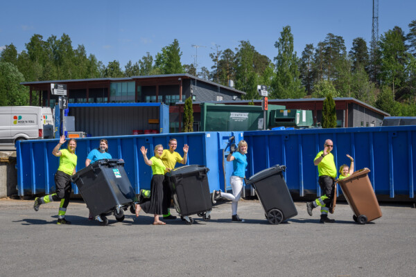 Joukko iloisia Rosk'n Rollin työntekijöitä työntää jäteastioita letkassa