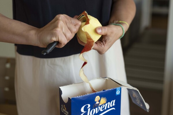 Woman peeling an apple, peel goes straight into an empty cardboard box for cereal.