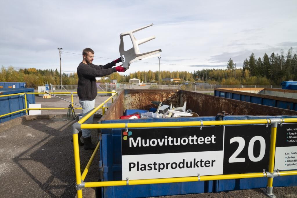 Asiakas tiputtamassa puutarhatuolia muovituotteiden lavalle jäteasemalla